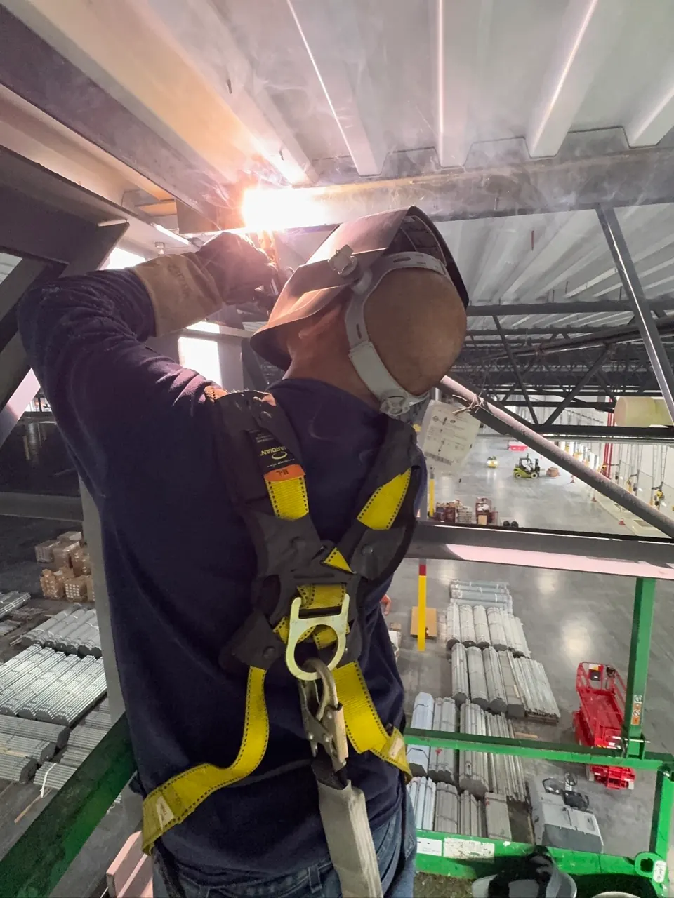 Welder working at height on a structural steel beam