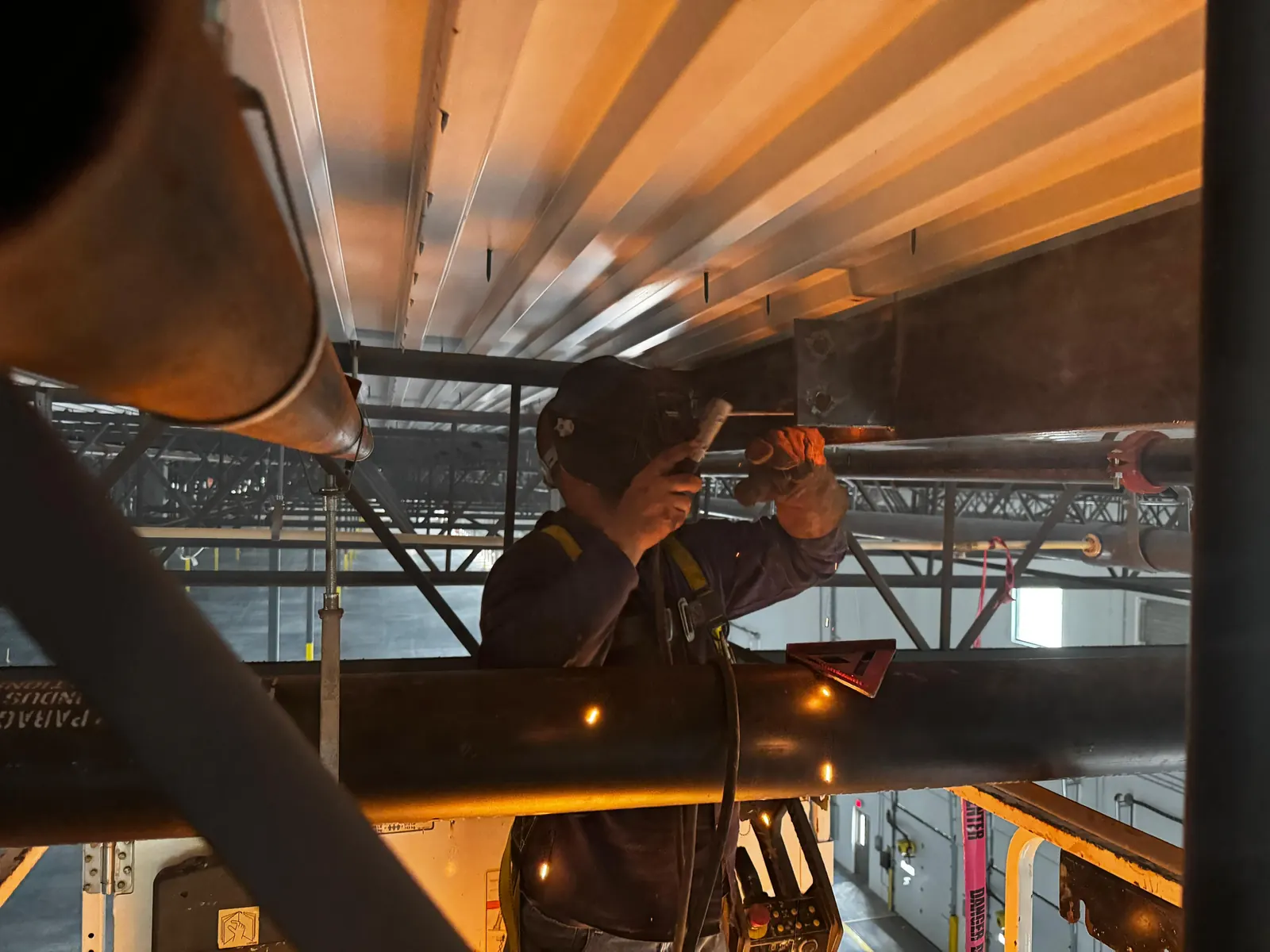 Welder working around overhead steel and piping