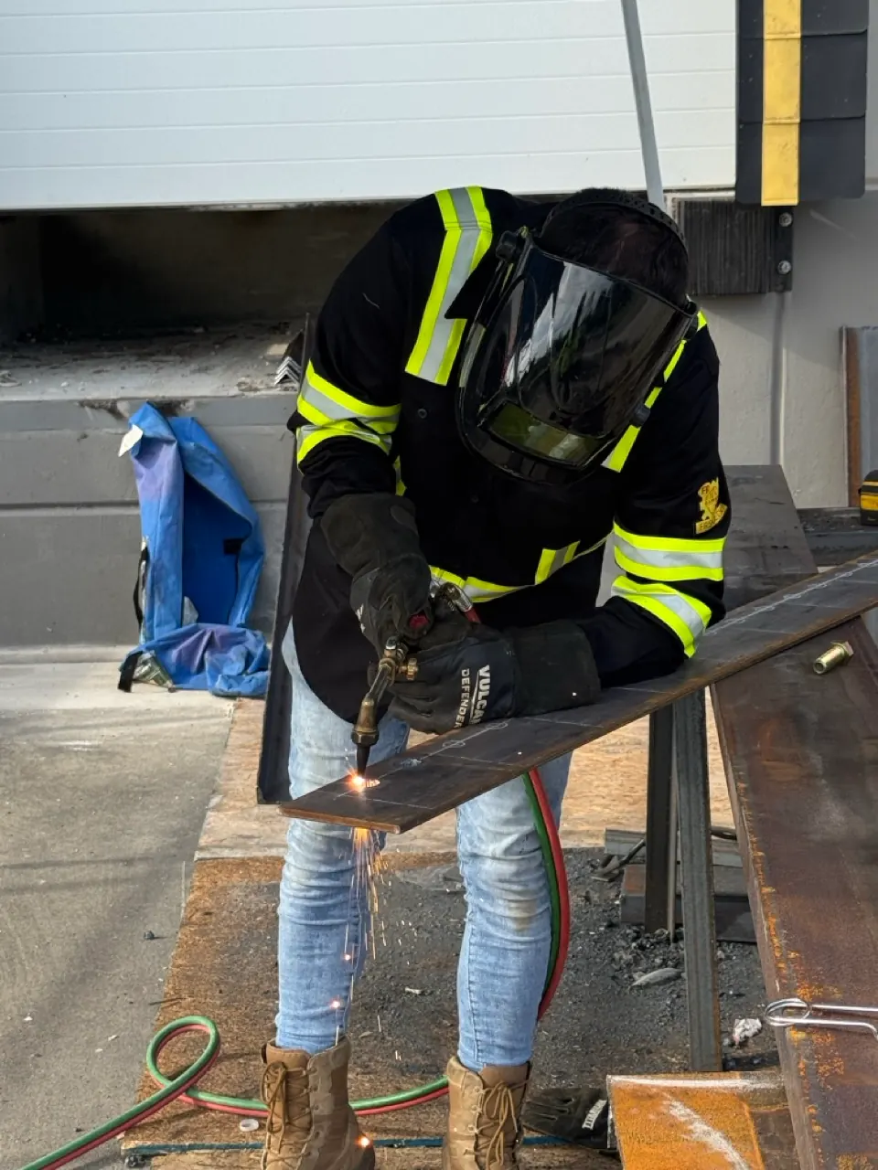 Welder cutting a steel plate with torch and sparks
